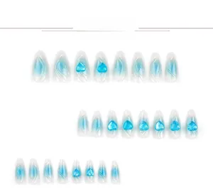 Detail view of almond nails with blue 3D heart charms and glitter gradient finish