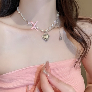 Détail du collier à chaîne argentée avec perles, nœud rose et pendentif en cœur