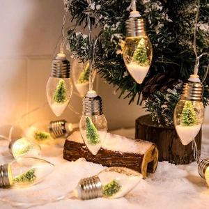 Close-up of LED decorative globe lights with miniature Christmas tree and snow scene inside