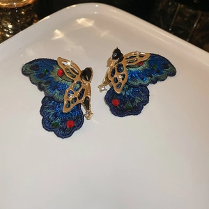 Close-up of asymmetrical butterfly earrings with blue embroidery and colorful crystals