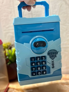Detail of blue electronic piggy bank with keypad and portable handle for children