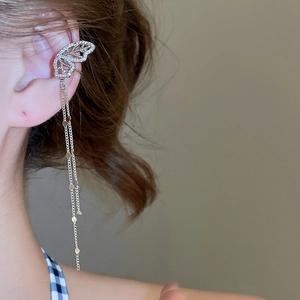 Macro detail of silver butterfly ear cuff with sparkling zircons and long tassel chains