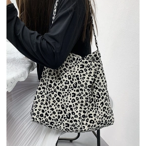 Detail of the high-capacity leopard print corduroy tote bag worn as a shoulder bag