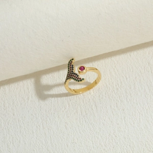 Détail de bague sirène avec zircons colorés et une pierre rose sur fond artistique