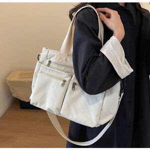 Detail of a large corduroy tote bag in creamy white with multi-pocket zipper design