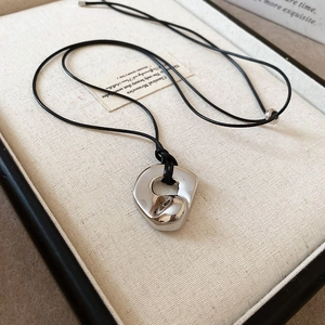 Detailed view of silver hollow double heart pendant on black cord in a jewelry box