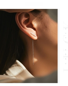 Detail of elegant 925 silver long tassel earrings with pearls on model with warm lighting