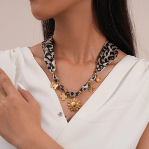 Detail of leopard print fabric necklace with golden sun and butterfly pendants on model