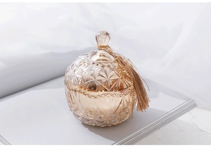 Detail of amber embossed glass jar with gold tassel lid on gray book surface
