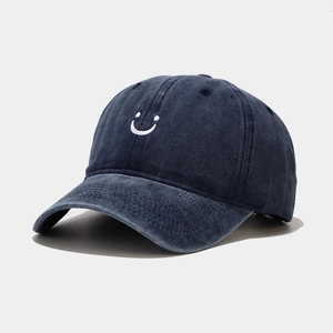 Detailed macro view of white embroidered smiley face on washed navy baseball cap