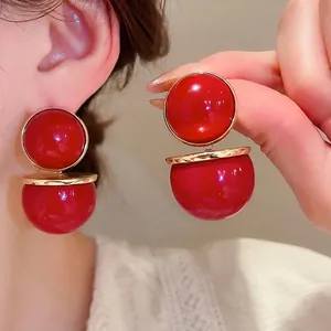 Boucles d'oreilles boules rouges avec anneaux dorés présentées sur un modèle en double vue
