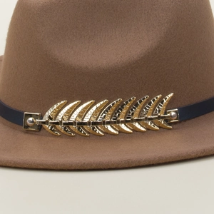 Close-up of golden leaf metal ornament on dark blue band of a brown wool fedora hat