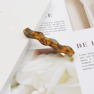 Detail of wavy acetate hair clip with tortoise shell pattern and gold metal spring clip