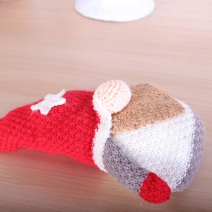 Knitted Christmas gnome doll with red and white wool texture on a light wood background