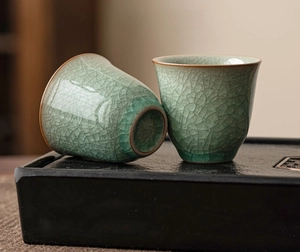 Close-up of celadon ice-cracked glaze Ru kiln ceramic tea cups on a dark wood tray