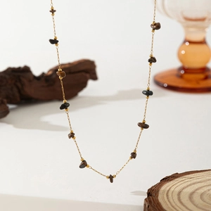 Detail of gold necklace with brown and black natural stone beads on a wooden texture