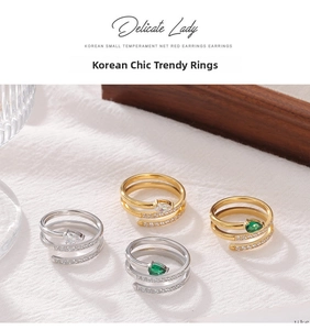 Macro detail of multi-layered spiral snake rings with pear-cut emerald and clear stones