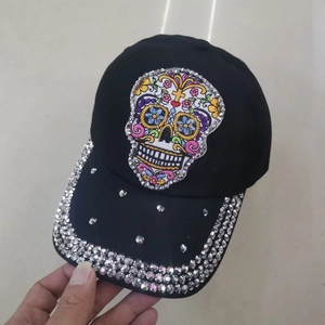 Close-up of a black denim baseball cap with sugar skull embroidery and silver rhinestones