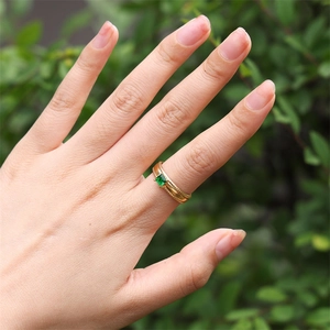 Detail of 18k gold plated ring with green square zircon gemstone worn on finger
