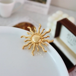 Close-up of vintage golden sunburst brooch with glossy finish on a white porcelain edge