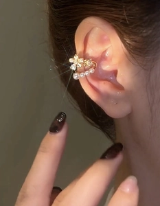 Detailed view of gold flower ear cuff with sparkling zircons and dangling white pearls