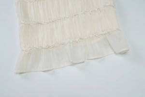 Dettaglio dell'orlo in chiffon e pizzo bianco sporco con volant a pieghe sottili