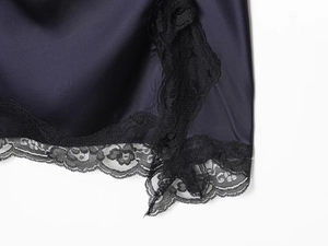 Gros plan sur le tissu en satin bleu foncé avec détails en dentelle noire raffinée