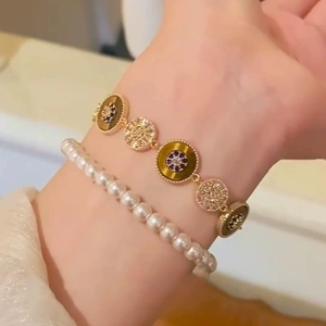 Close-up of 18k gold plated tiger eye bracelet and pearl jewelry set worn on wrist