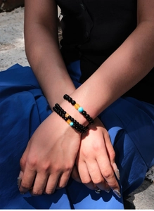 Detail of beaded bracelet set featuring black, yellow, and blue agate beads on wrist
