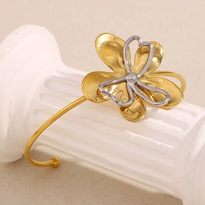 Artistic detail of two-tone flower cuff bracelet on a white Roman column display