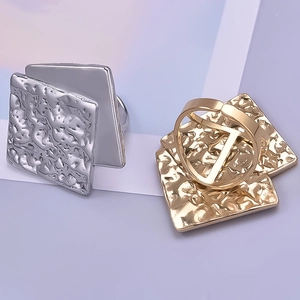Detailed macro view of square gold and silver adjustable rings with hammered metal texture