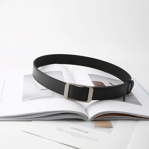 Minimalist black leather belt with matte silver buckle displayed on a white book