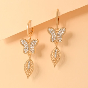 Detailed macro view of champagne gold butterfly earrings with zircon leaf pendants
