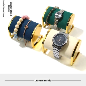 Golden C-shaped jewelry stands for watches and bracelets with emerald, blue, and white velvet