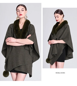 Detail of dark green knit shawl featuring a faux rabbit fur collar and decorative pom-poms