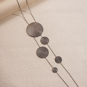Macro shot of long necklace with five circular textured metal pendants in gunmetal finish