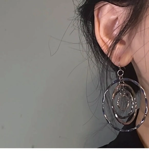 Detailed close-up of tiered silver spiral hollow dangle earrings on a model