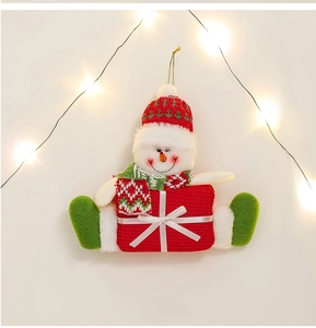 Festive knitted snowman pendant with a red gift box hanging on Christmas tree lights
