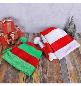 Close-up of plush striped Christmas hats with pom-poms on wooden festive background