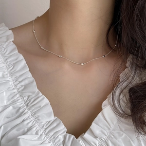 Close-up of minimalist 925 sterling silver olive bead chain necklace on model neck