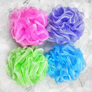 Top view of colorful mesh bath sponges in pink, purple, green and blue on marble tiles