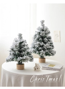 Close-up of snow-flocked mini Christmas trees on wooden bases for tabletop holiday decor
