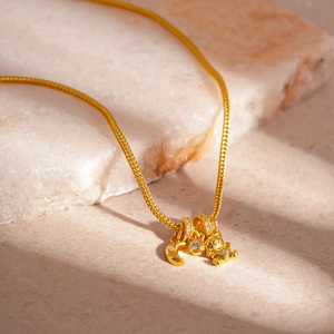 Close-up of a gold-toned necklace with moon, bear charms, and zircon on stone