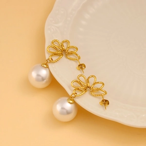 Detail of golden floral wreath earrings with large white pearls on a lace porcelain plate