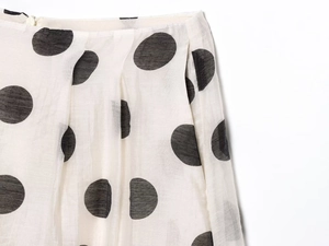 Detailed view of white polka dot fabric featuring a side zipper closure on a skirt