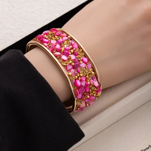 Wide gold cuff bracelet with pink gravel stones and pyramid studs in bohemian style