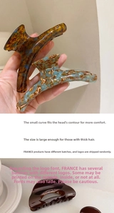 Detail of ergonomic acetate hair claw clip showing tortoise shell and marble textures