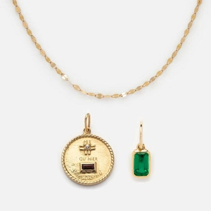 Close-up of gold stainless steel necklace with green zircon stone and engraved charm