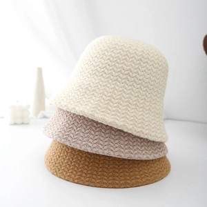 Three knitted bucket hats in beige, pink, and brown with thick V-stitch winter design