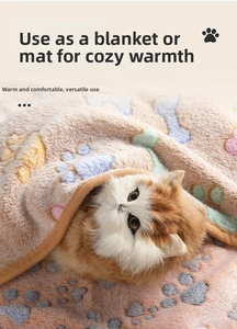 Close-up of a warm coral fleece pet blanket with colorful paw and bone prints